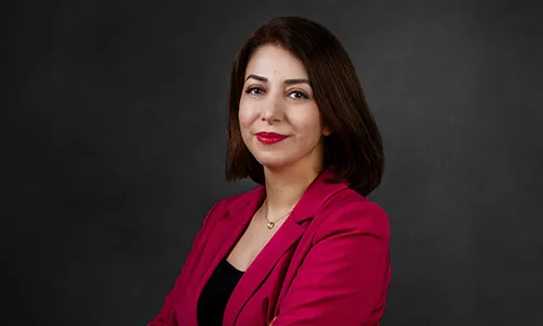 Portrait professionnel d'une femme de trois-quarts en veste fuchsia, bras croisés, réalisé par Laurène Zabary, photographe à Paris.