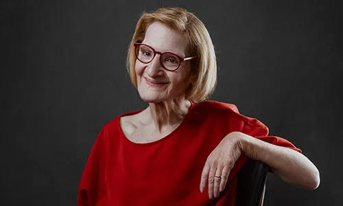 Portrait professionnel d'une femme de trois-quarts en haut rouge, accoudée au dossier d'une chaise, réalisé par Laurène Zabary, photographe à Paris.