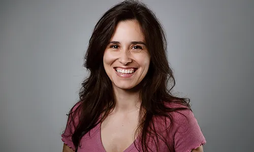Portrait de Maeva Balan, comédienne souriante, posant de face en haut rose, réalisé par Laurène Zabary, photographe à Paris.