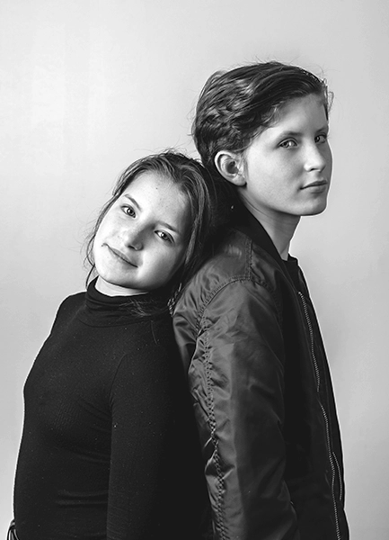 Deux enfants posent dos à dos en noir et blanc.