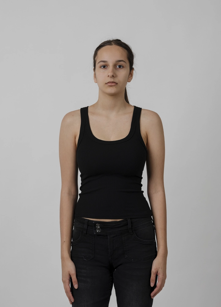 Polaroid mannequin d’Alyaa en pied de face, tenue noire sobre, réalisé en studio à Paris.