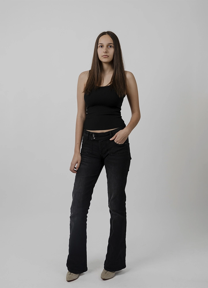 Polaroid mannequin d’Alyaa en pied de face, tenue noire sobre, réalisé en studio à Paris.