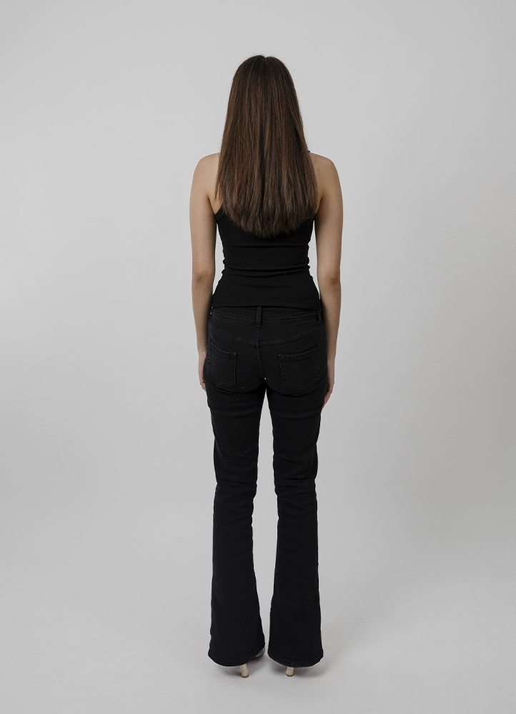 Polaroid mannequin d’Alyaa en pied de face, tenue noire sobre, réalisé en studio à Paris.