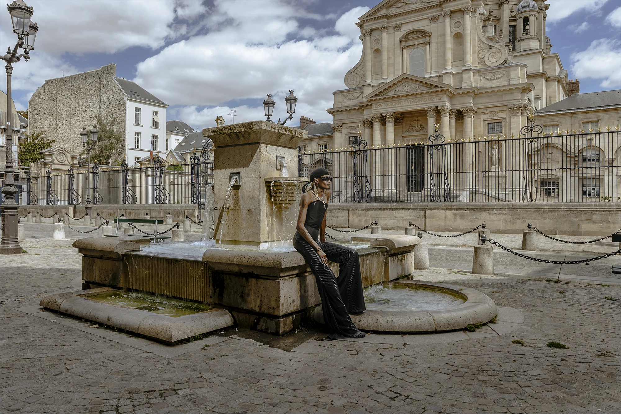 Be Norman assis près de la fontaine du Val-de-Grâce pendant un shooting mode à Paris.