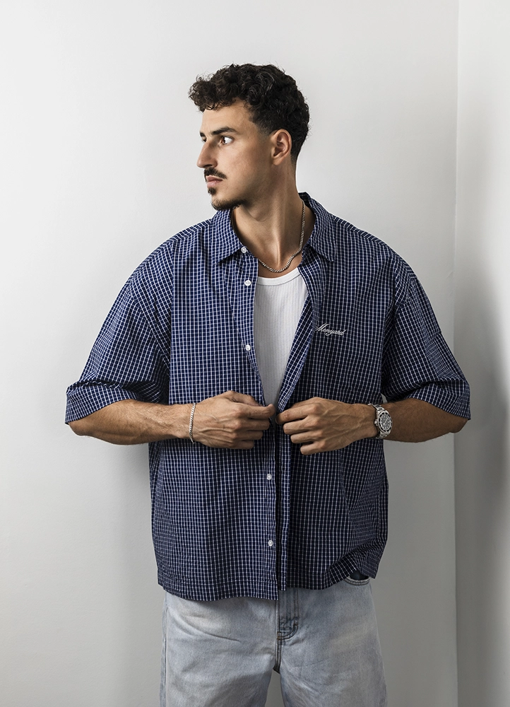 Portrait de Noam en chemise bleue, regard de côté, lors de son premier book photo en studio à Paris.