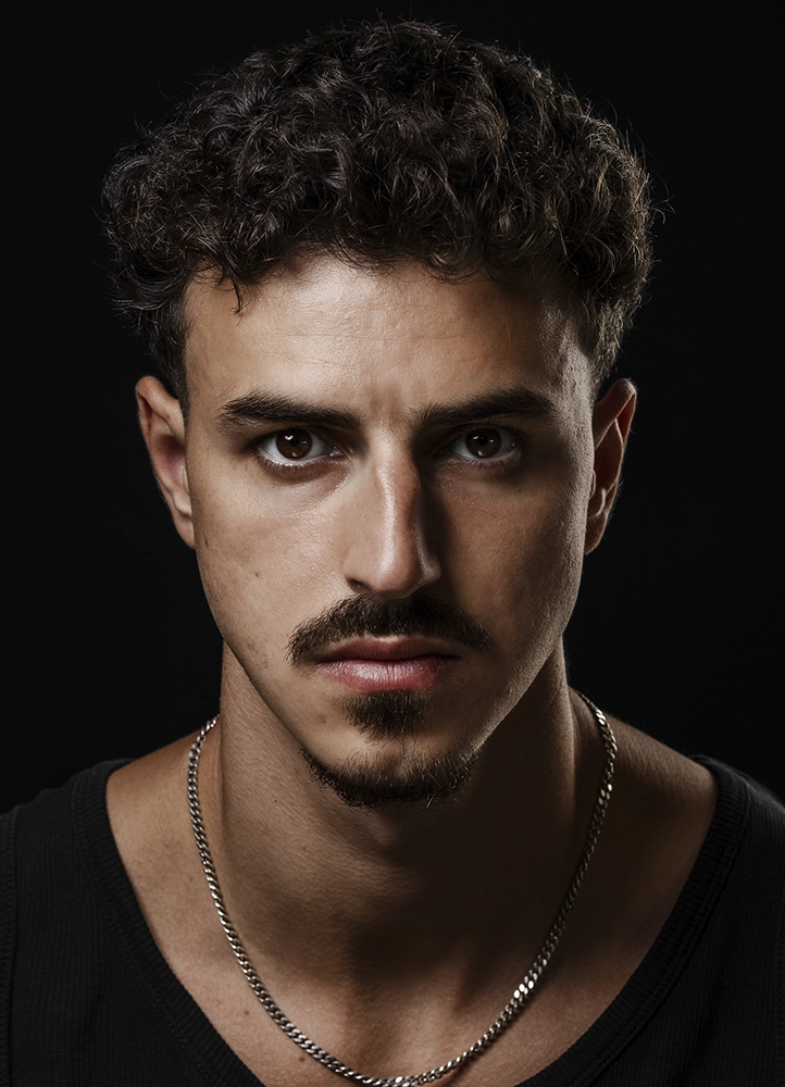 Gros plan de Noam face à l’objectif sur fond noir, réalisé lors d’une séance book photo en studio à Paris.