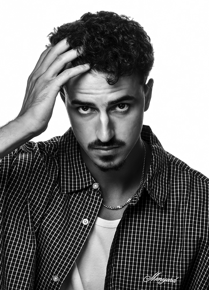 Portrait noir et blanc de Noam, main dans les cheveux et regard caméra, réalisé en studio à Paris.