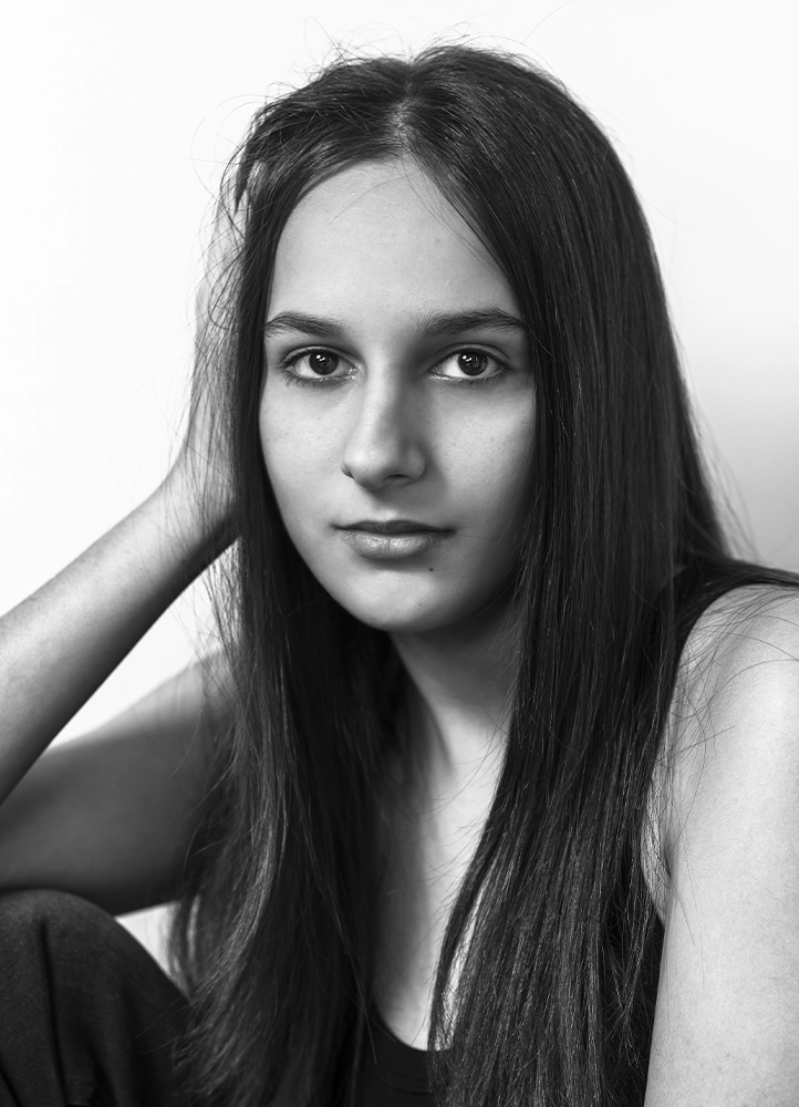 Portrait éditorial d’Alyaa assise dans un angle du studio, photographiée à Paris