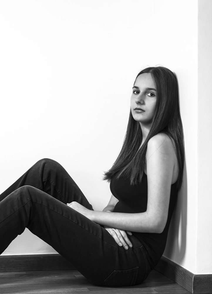 Portrait éditorial d’Alyaa assise dans un angle du studio, photographiée à Paris