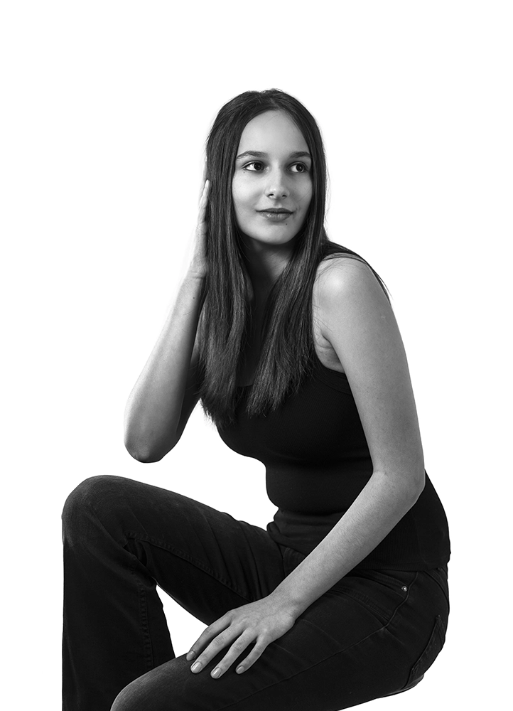 Portrait éditorial d’Alyaa assise dans un angle du studio, photographiée à Paris